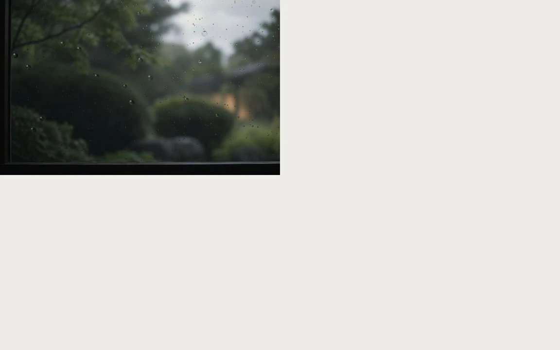 雨粒のついた窓の向こうに、柔らかくぼけた庭。しずくが光を拾い、ガラスを伝う。